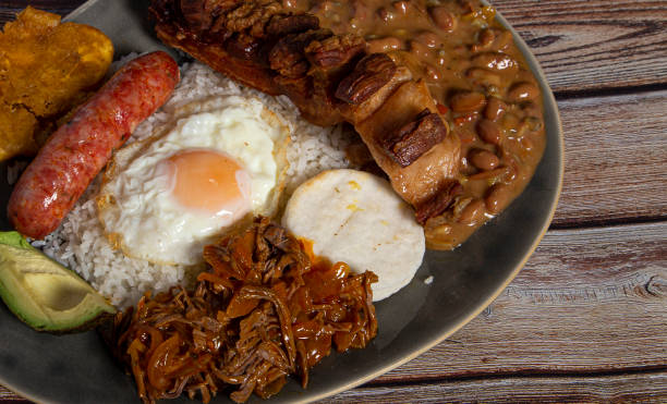 bandeja paisa, plat typique de la colombie. il se compose de chicharrón (ventre de porc frit), boudin noir, saucisse, arepa, haricots, banane frite, oeuf d’avocat et riz - bandeja paisa photos et images de collection