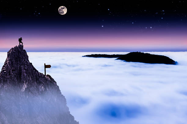 Hiker on Top of a Mountain Looking Over the Cloud Cover at Night