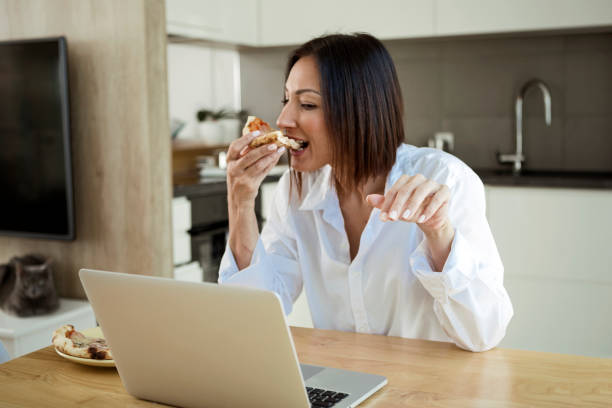 istock Woman working on laptop and eating pizza 1296521962