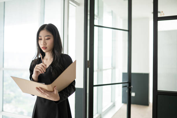 istock Asian Chinese white collar worker woman writing down note in her work place. 1296523361