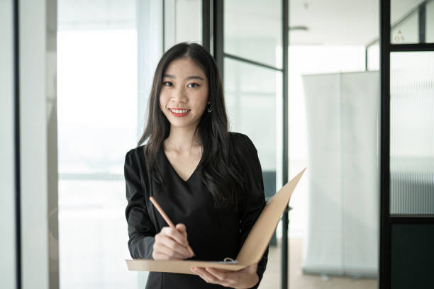 istock Asian Chinese white collar worker woman writing down note in her work place. 1296523368