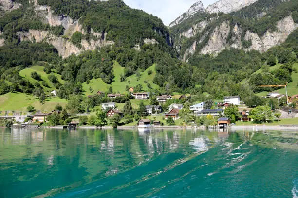 Between the giant mountain and the lake there are several buildings of a small village.