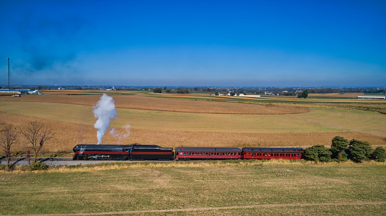 Aerial View of a Restored Antique Steam Locomotive Pulling Passenger Cars on a Sunny Fall Day
