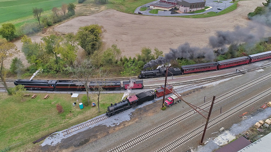 Aerial View of 3 Antique Restored Steam Locomotives Steamed Up and Moving Around in a Freight Yard