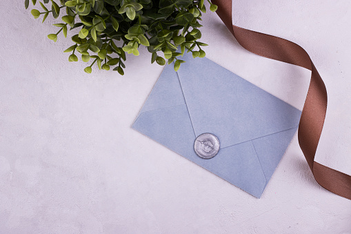 Blue handmade paper envelope with love wax seal, green plant in the background. love note for Valentine's day, mother's day