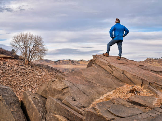 ロッキー山脈のふもとにある岩の崖の上の男性ハイカー - fort collins rock cliff mountain range ストックフォトと画像