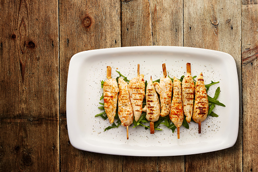 Directly above shot of grilled paprika chicken skewers on a bed of rocket served in a plate