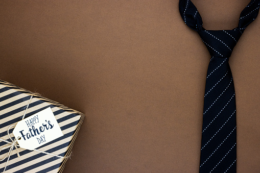 A gift box with the inscription happy father's day with a tie on a chocolate background. background for the dad's day holiday