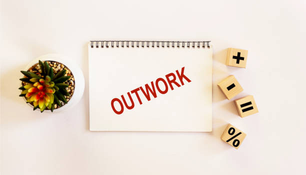 istock OUTWORK , the text is written on a notebook and a white background. On the table are wooden cubes with signs and there is a cactus flower 1296530256