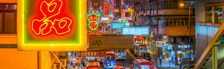 Elevated panoramic view across the vibrant neon signs and busy city streets of Kowloon at night, Hong Kong, China.