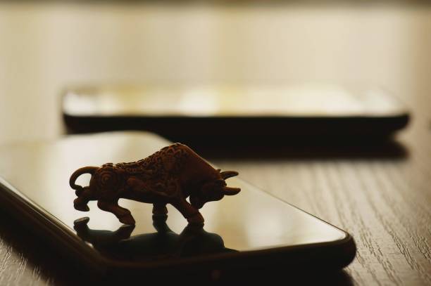 istock Metal bull and mobile phone on the table. 1296534095