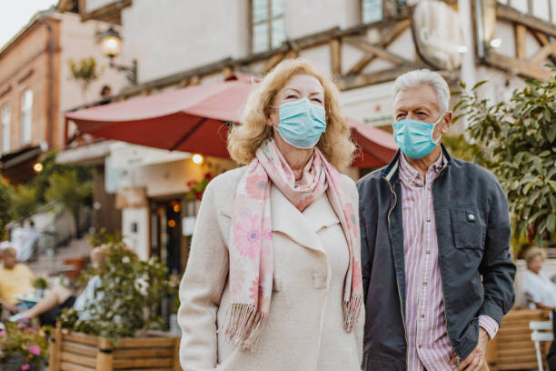 istock Senior couple on the street with protective masks 1296536792