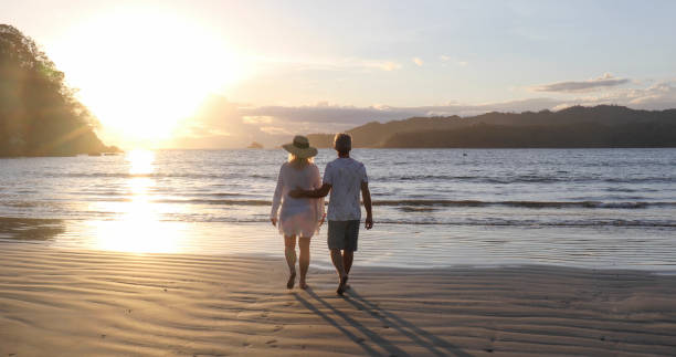 istock Mature couple walk along beach at sunrise 1296537313