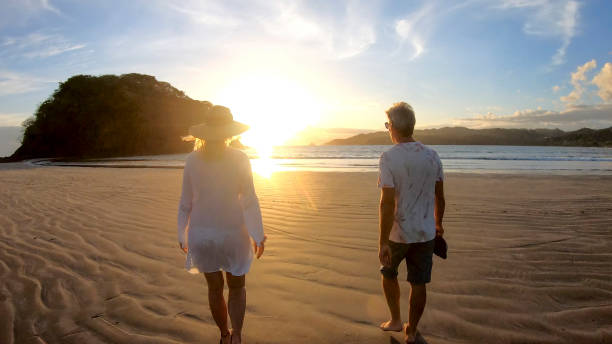 istock Mature couple walk along beach at sunrise 1296537334