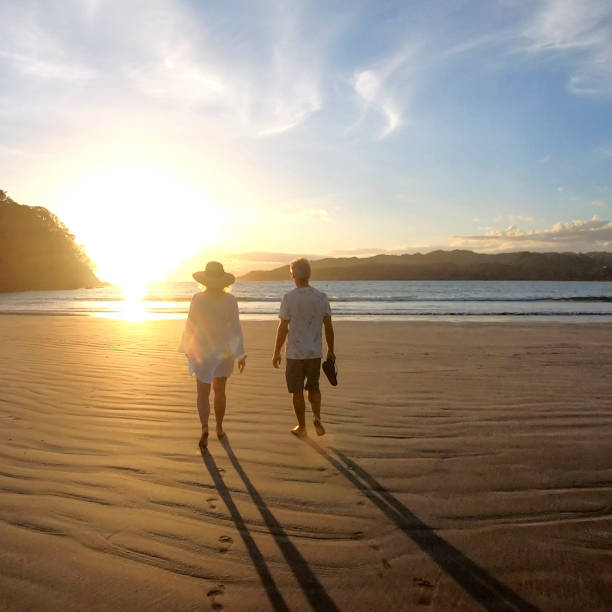 istock Mature couple walk along beach at sunrise 1296537383