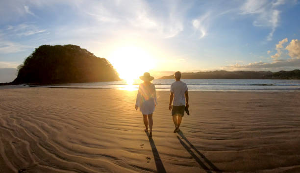 istock Mature couple walk along beach at sunrise 1296537388