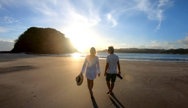 istock Mature couple walk along beach at sunrise 1296537395