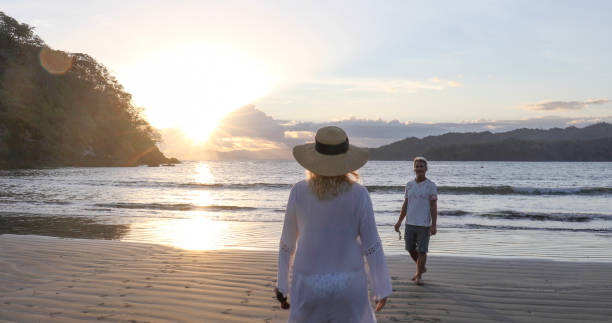 istock Mature couple walk along beach at sunrise 1296537548