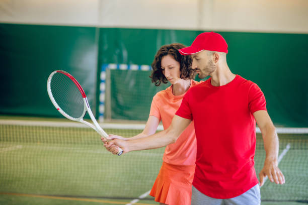 istock Man in a red cap and with a racket having a workout with his female coach 1296538785