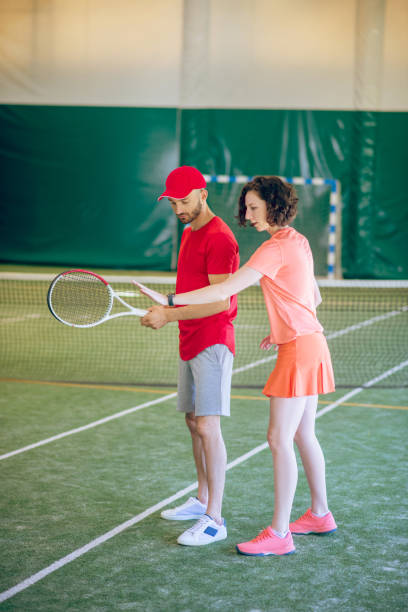 istock Man in a red cap and with a racket having a workout with his coach 1296538795