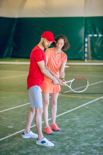 istock Tennis coach in red cap training a dark-haired woman 1296538807