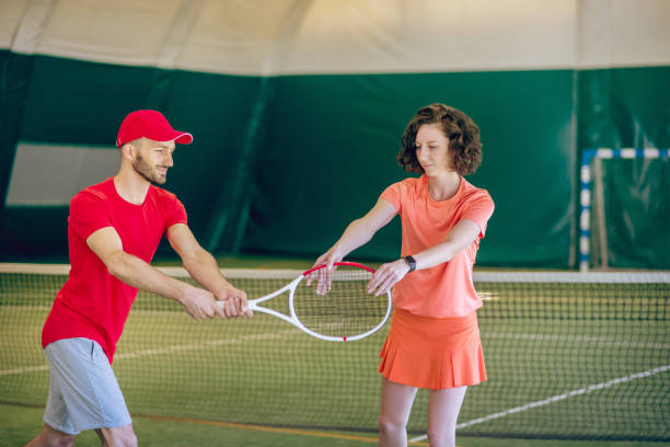 istock Man in a red cap and with a racket having a workout with his female coach 1296538815