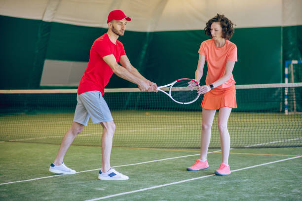 istock Young man in a red cap and with a racket having a workout with his female coach 1296538827