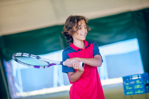 istock Dark-haired boy standing with a tennis racket in his hand 1296538839