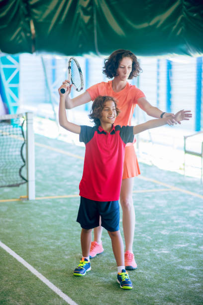 istock Dark-haired boy having a tennis workout with his coach 1296538880