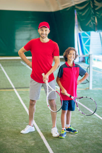 istock Coach in a red cap and a boy spending time playing tennis 1296538934
