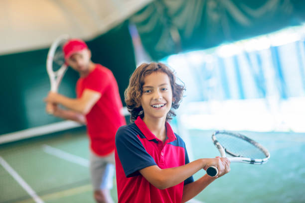 istock Coach in a red cap and a boy spending time playing tennis 1296538936