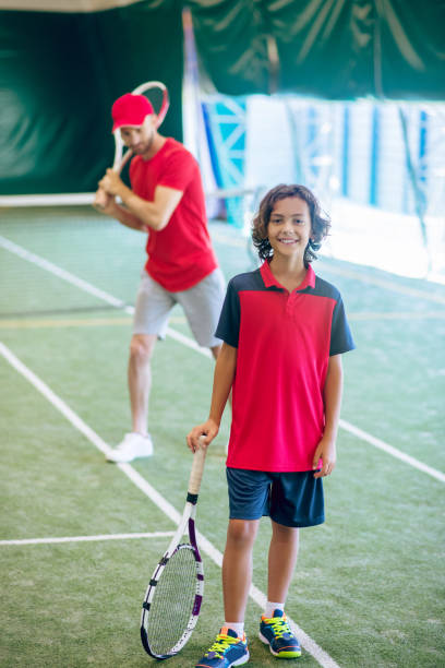 istock Cute dark-haired boy standing with a tennis racket and smiling 1296538937