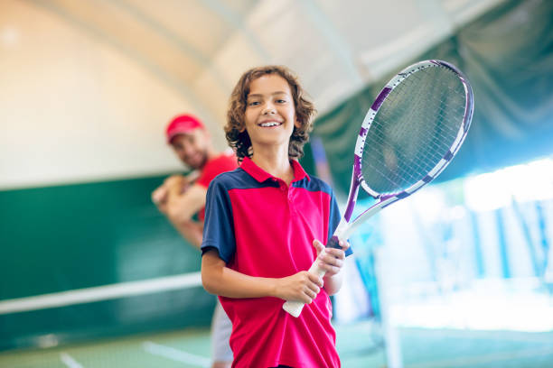 istock Cute dark-haired boy standing with a tennis racket and smiling 1296538942