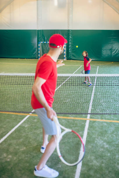 istock Coach in red clothes and cap playing tennis with a boy 1296538985