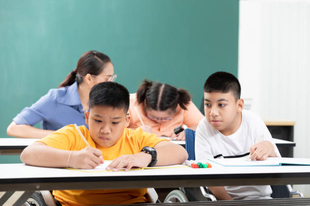 istock asian disabled kids or autism child learning looking and writing at desks in classroom 1296540001