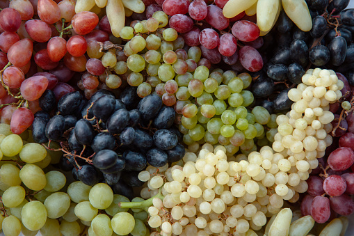 Red grapes with green grape leaves on white background.