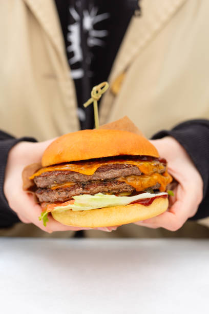 istock Woman's hands holding juicy bun burger with meat 1296542694