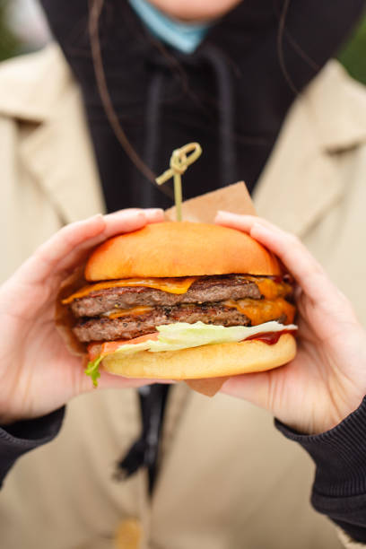 istock Woman's hands holding juicy bun burger with meat 1296542703