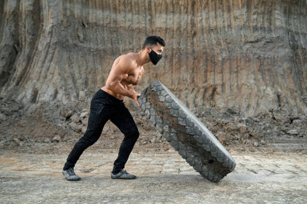 istock Muscular man in face mask workout with heavy wheel 1296543547