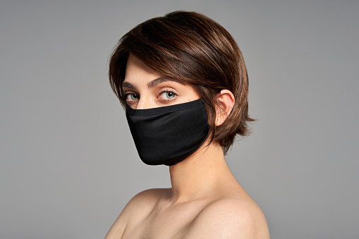 Close-up portrait of girl with protection flu cold facial mask isolated over gray background