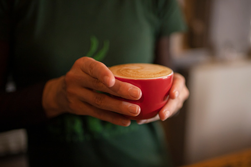 Man's hands holding red cup of coffee. Closeup. Side view.