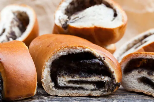 the filling of poppy seeds and eggs in a dessert bun with fresh bun with a black filling of poppy seeds, a close-up of delicious fresh wheat buns, flesh cut into pieces