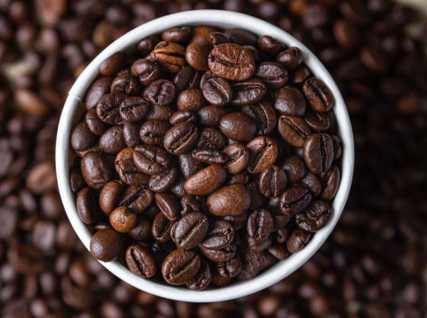 istock Takeaway coffee recycle cup with roasted coffee beans on coffee beans background. Top view. Close up. 1296551551