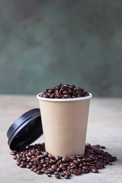 istock Takeaway coffee cup and roasted coffee beans, light concrete background. Coffee shop concept. 1296551756