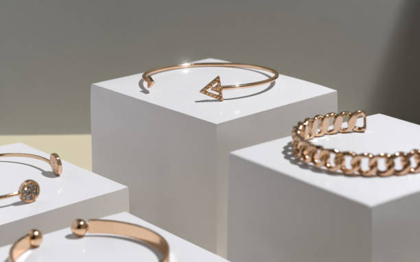 istock Modern golden arrow shape bracelets on white cubes 1296551963