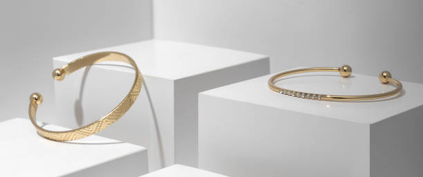 istock Two modern Golden bracelets on white geometric cubes 1296551964