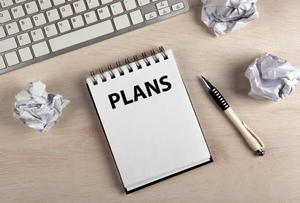 istock work table, a notebook with title plans a pen and crumpled paper top view 1296553614