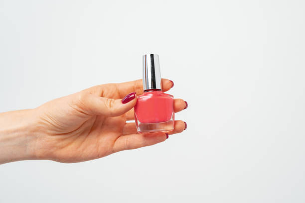 istock Female hand holding nail polish against white background 1296555712