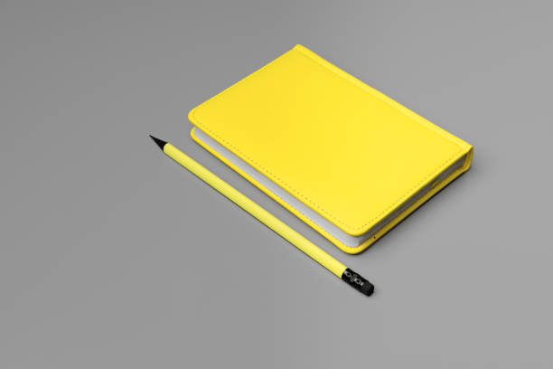 istock Yellow notepad with yellow pencil on gray background 1296556423