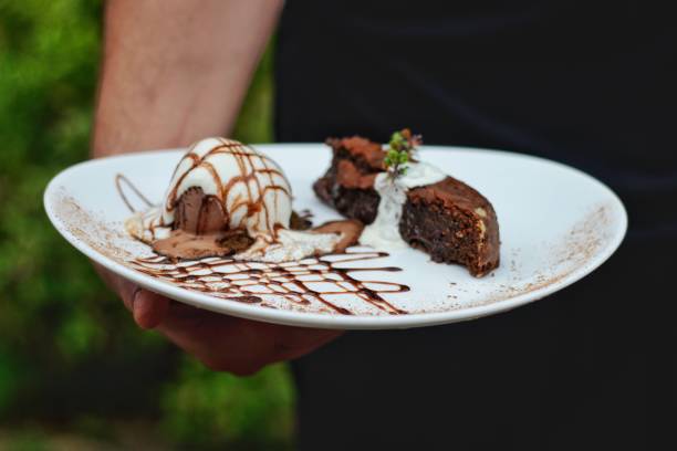 istock hand holding brownie plate with ice cream 1296558711